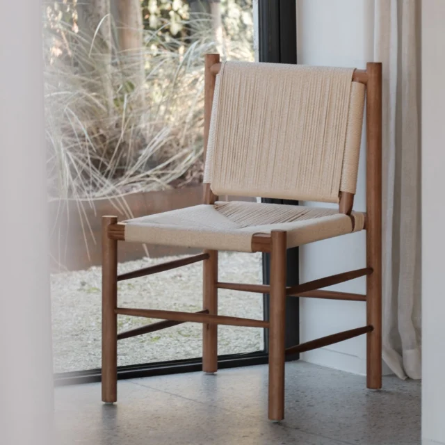 The Panama dining chair brings artisanal craftsmanship to the modern table. Construct ed from solid ash wood in a rich walnut stain, its frame highlights clean, linear proportions softened by rounded corners and finely sanded f inishes. The defining feature is its handwoven seat and backrest, crafted from natural rope in a warm flax tone.
